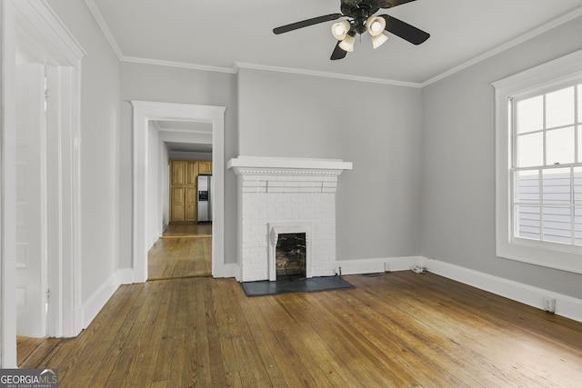 unfurnished living room with baseboards, ceiling fan, ornamental molding, hardwood / wood-style flooring, and a brick fireplace