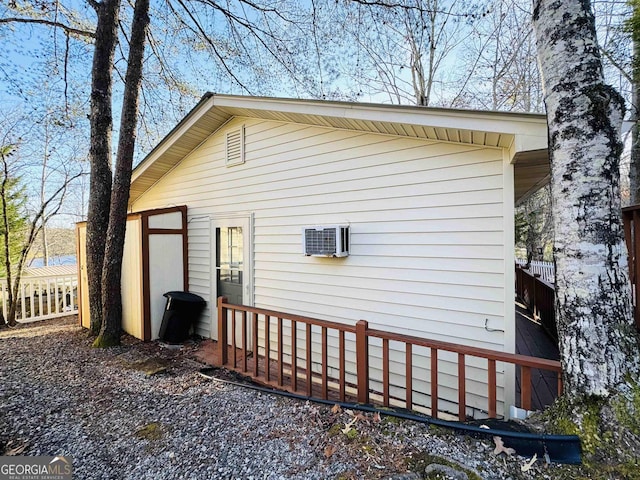 view of side of home featuring an AC wall unit and fence