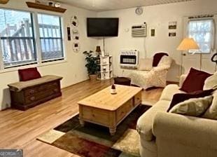 living room featuring heating unit, a wall unit AC, and wood finished floors