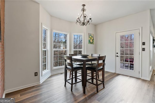 dining area with dark wood finished floors, baseboards, and an inviting chandelier