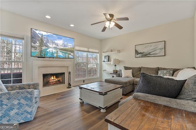 living area with a fireplace with flush hearth, recessed lighting, a ceiling fan, and wood finished floors