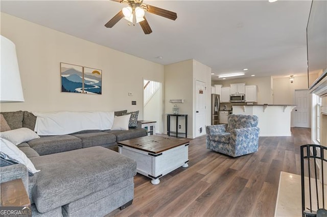 living area featuring baseboards, dark wood-type flooring, a ceiling fan, and recessed lighting