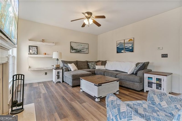 living area featuring a ceiling fan, baseboards, and wood finished floors