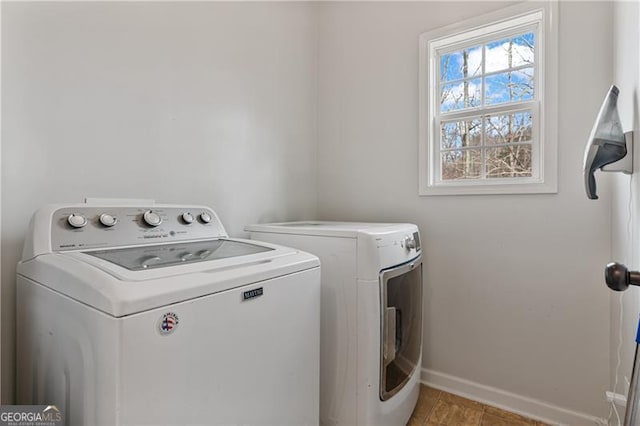 clothes washing area with washer and dryer, laundry area, and baseboards