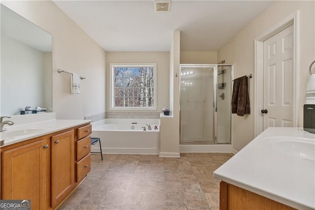 bathroom with a stall shower, two vanities, a sink, and visible vents