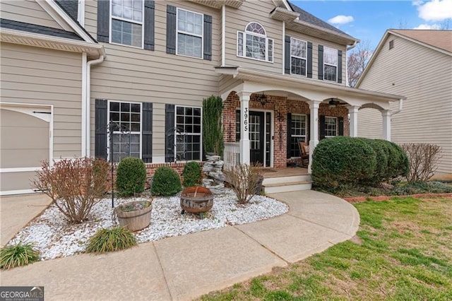 doorway to property with covered porch and brick siding