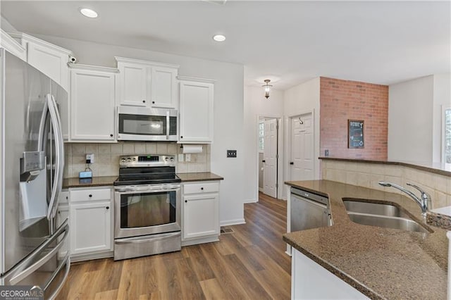 kitchen featuring appliances with stainless steel finishes, backsplash, a sink, and wood finished floors