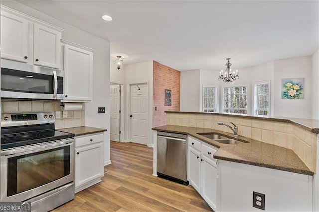 kitchen with decorative backsplash, appliances with stainless steel finishes, light wood-style floors, white cabinetry, and a sink