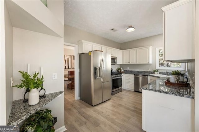 kitchen with visible vents, appliances with stainless steel finishes, white cabinetry, and light wood-style floors