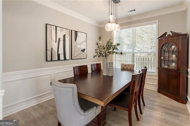 dining room with ornamental molding, light wood-style flooring, and visible vents