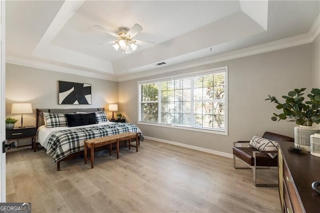 bedroom featuring baseboards, crown molding, a raised ceiling, and light wood-style floors