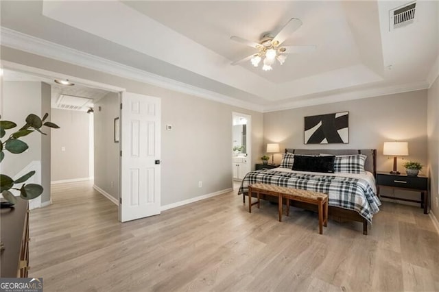 bedroom with visible vents, baseboards, ornamental molding, light wood-type flooring, and a tray ceiling