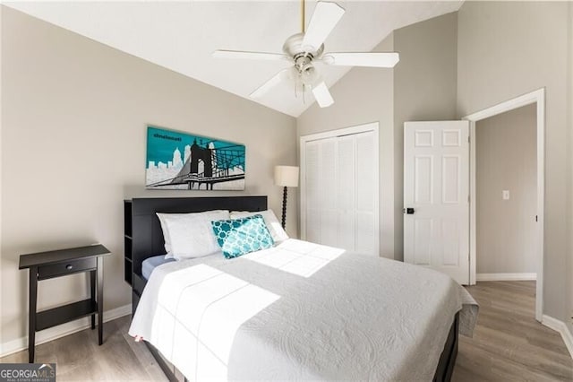 bedroom with a closet, a ceiling fan, vaulted ceiling, wood finished floors, and baseboards