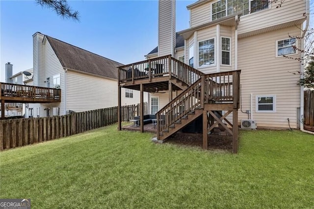 rear view of property with a fenced backyard, stairway, a lawn, and a wooden deck