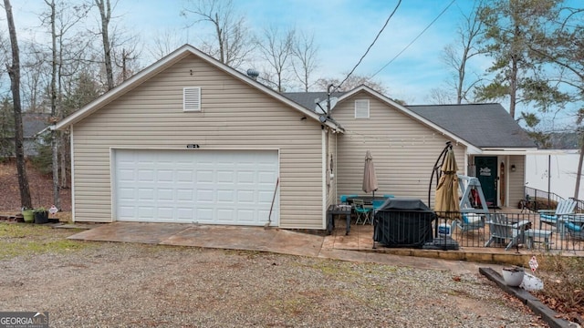 back of property with an attached garage and dirt driveway