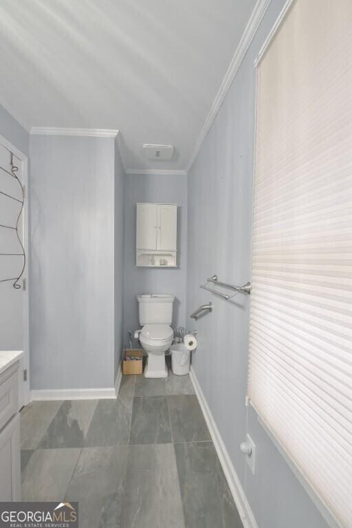 bathroom with vanity, toilet, crown molding, and baseboards