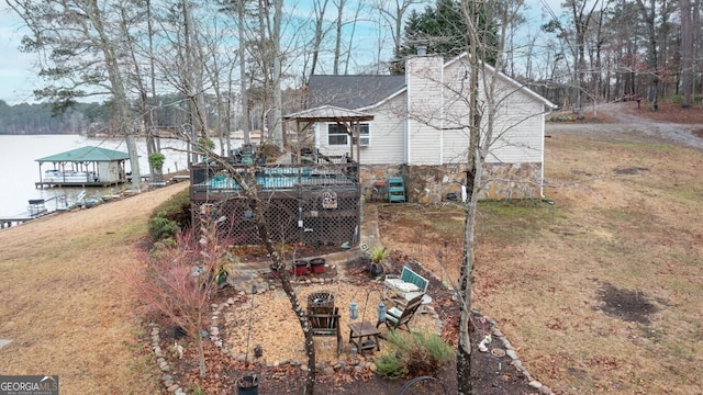 exterior space with a chimney, a lawn, a wooden deck, and roof with shingles