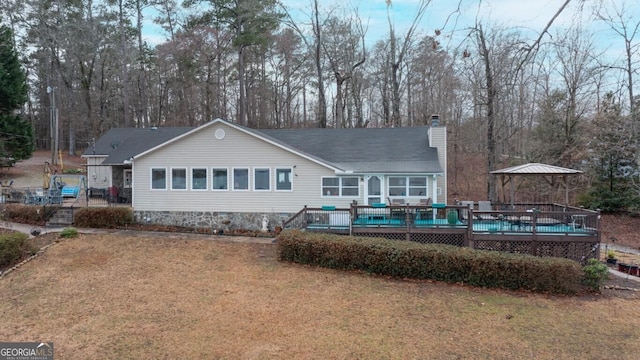 back of house featuring a yard, a deck, and a chimney