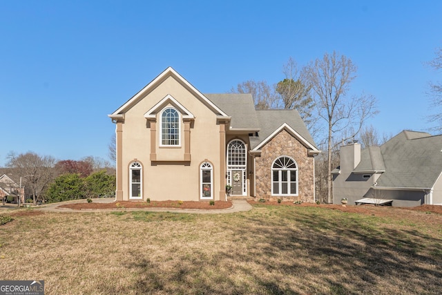 traditional-style house with a front yard, stone siding, and stucco siding