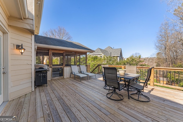 wooden deck with outdoor dining space, a sunroom, and a grill