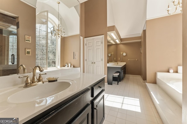 full bath with an inviting chandelier, two vanities, a sink, tile patterned floors, and a bathtub