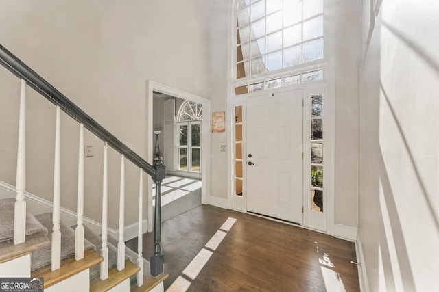 entryway featuring stairway, baseboards, a high ceiling, and wood finished floors