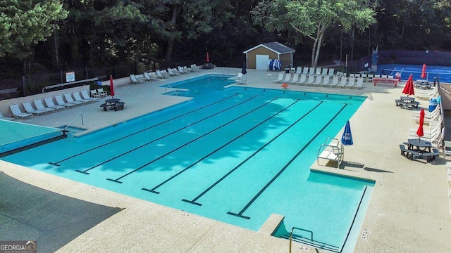 community pool featuring a patio, a fire pit, and fence