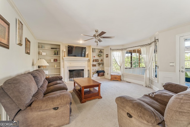 living area with built in shelves, a fireplace, carpet floors, and ornamental molding