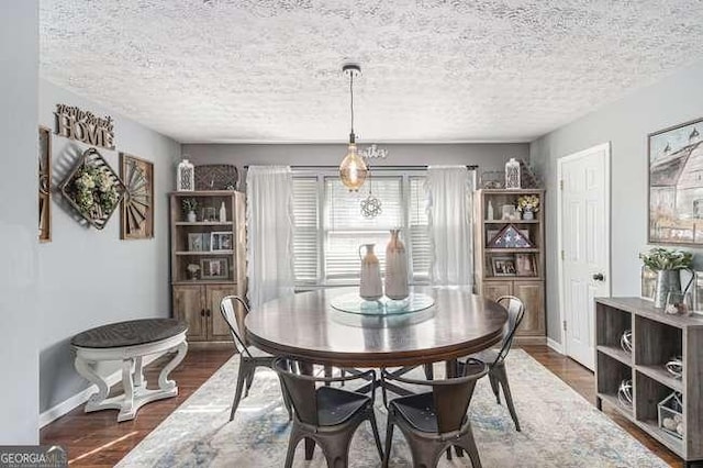 dining space with baseboards, dark wood-style flooring, and a textured ceiling