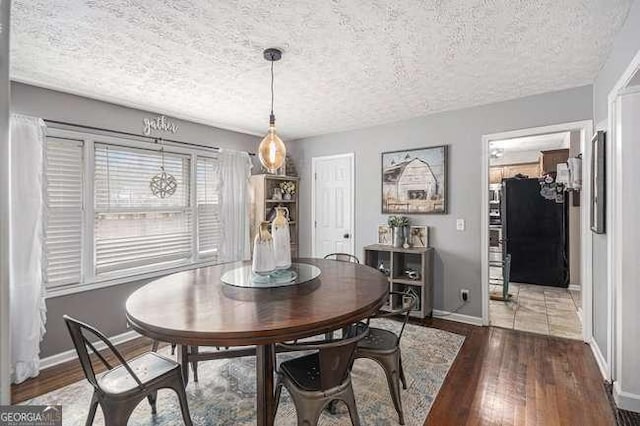 dining area featuring hardwood / wood-style floors, baseboards, and a textured ceiling