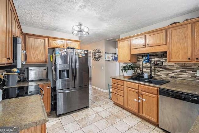 kitchen featuring a sink, a textured ceiling, stainless steel appliances, light tile patterned floors, and decorative backsplash