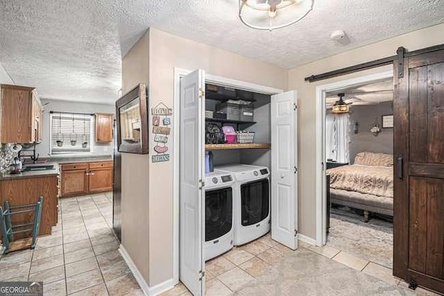 kitchen featuring light tile patterned floors, washing machine and clothes dryer, a textured ceiling, a barn door, and brown cabinets