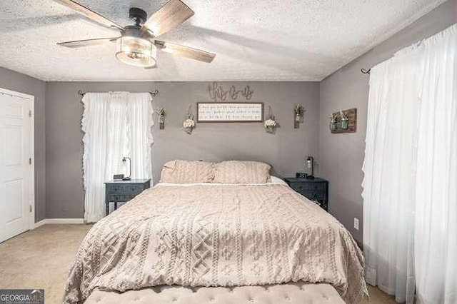 bedroom with a ceiling fan, baseboards, a textured ceiling, and carpet flooring