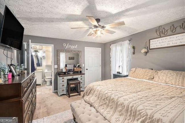 bedroom with a textured ceiling, ensuite bathroom, and a ceiling fan