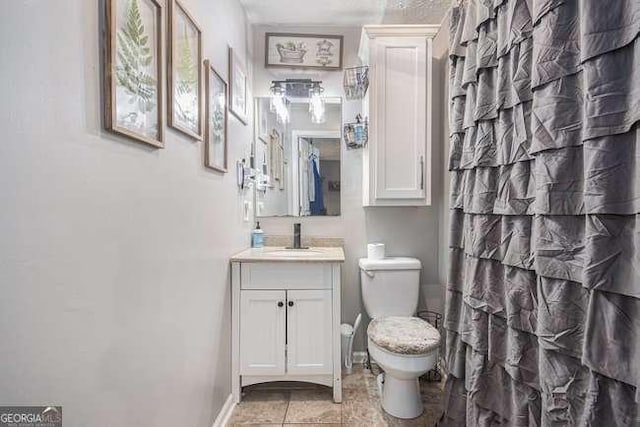 full bathroom featuring baseboards, toilet, and vanity