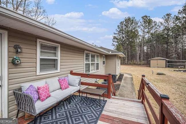 wooden terrace featuring an outdoor living space, a storage unit, and an outbuilding