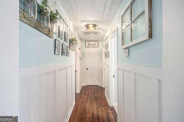 hallway featuring visible vents, attic access, and dark wood-style floors