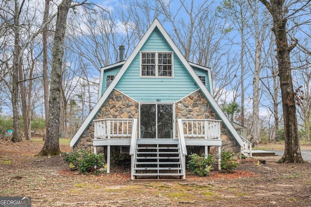 rear view of property featuring a wooden deck, stone siding, and stairs