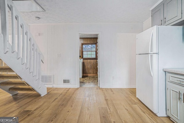 kitchen featuring visible vents, gray cabinetry, light wood-style flooring, and freestanding refrigerator