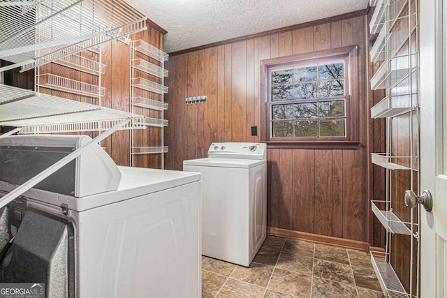 clothes washing area featuring washer and clothes dryer, laundry area, wood walls, and a textured ceiling