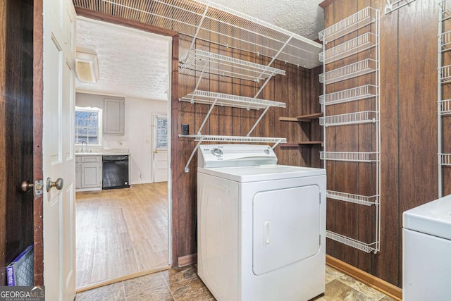 laundry area featuring a sink, a textured ceiling, washer / dryer, and laundry area