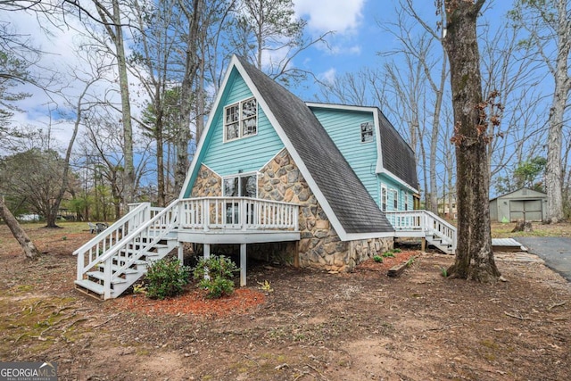 view of front of home featuring a wooden deck, stone siding, and a shingled roof