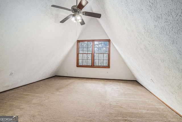 carpeted spare room featuring lofted ceiling, a ceiling fan, and a textured ceiling