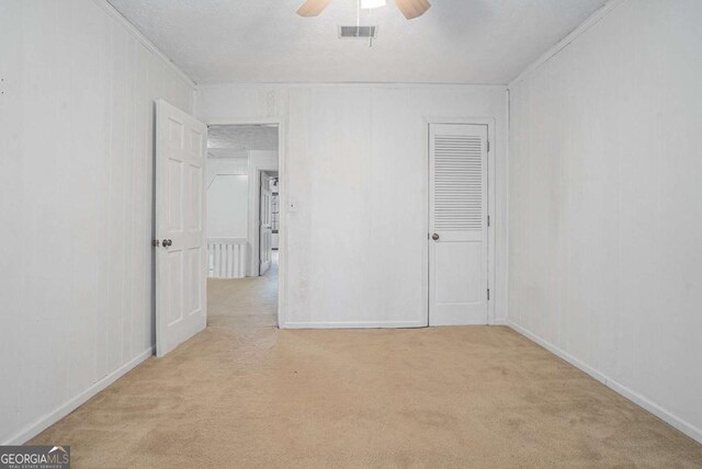 unfurnished bedroom featuring visible vents, carpet floors, a textured ceiling, and a ceiling fan