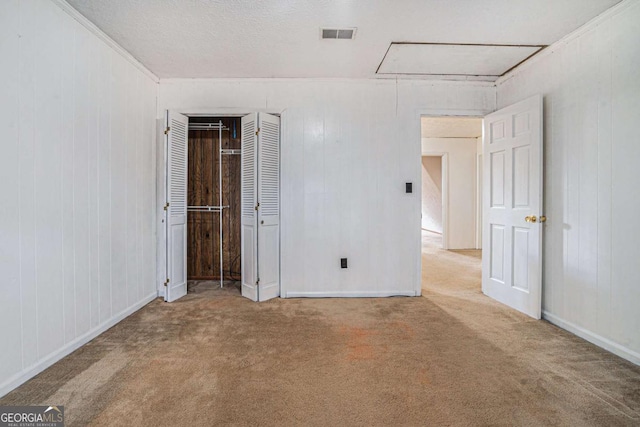 unfurnished bedroom featuring a closet, visible vents, attic access, and carpet