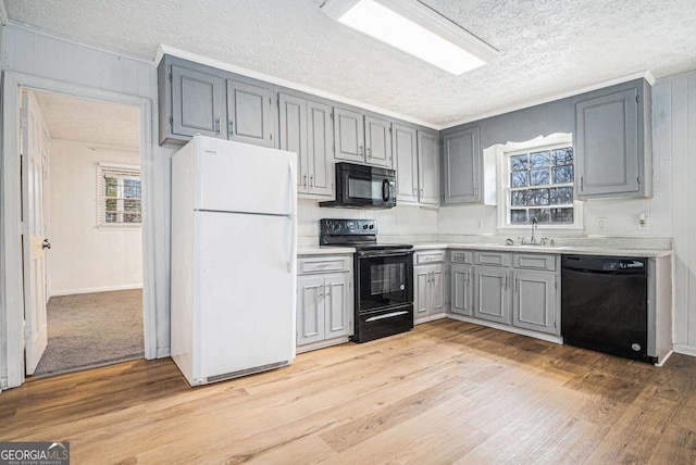 kitchen featuring a wealth of natural light, gray cabinets, black appliances, and light countertops