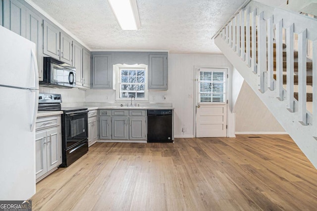 kitchen featuring light wood-type flooring, plenty of natural light, black appliances, and gray cabinets