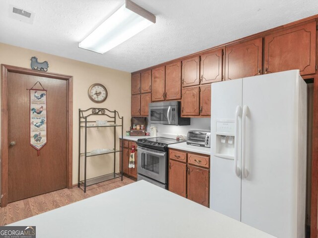 2643 Rocky Creek Rd, Hampton, GA 30228 - kitchen with visible vents, light wood finished floors, stainless steel appliances, light countertops, and a textured ceiling