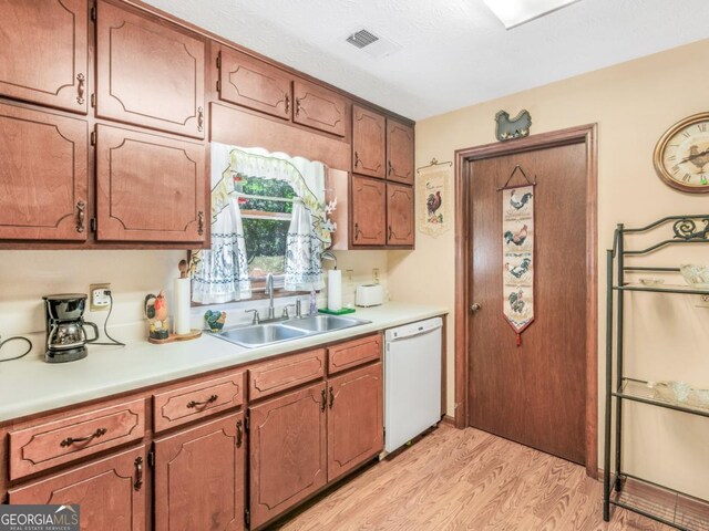 2643 Rocky Creek Rd, Hampton, GA 30228 - kitchen featuring a sink, light wood-style floors, brown cabinetry, white dishwasher, and light countertops