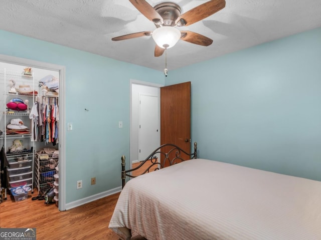 2643 Rocky Creek Rd, Hampton, GA 30228 - bedroom featuring a walk in closet, baseboards, wood finished floors, a closet, and a ceiling fan